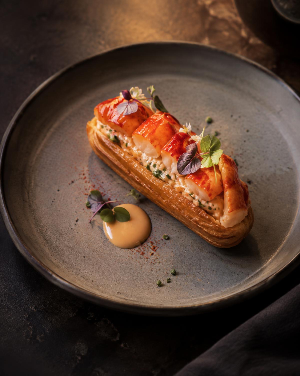 Crisp crayfish pastry with sauce and micro herbs on a dark stone plate